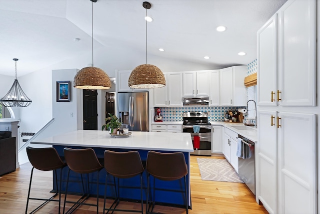 18017 N Lidgerwood Ct, Colbert, WA 99005 - kitchen with stainless steel appliances, under cabinet range hood, lofted ceiling, tasteful backsplash, and light wood finished floors