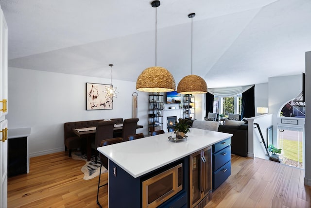 18017 N Lidgerwood Ct, Colbert, WA 99005 - kitchen with blue cabinets, stainless steel microwave, light wood-style floors, wine cooler, and a breakfast bar