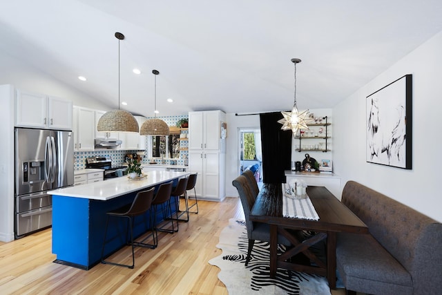 18017 N Lidgerwood Ct, Colbert, WA 99005 - kitchen featuring appliances with stainless steel finishes, vaulted ceiling, white cabinets, tasteful backsplash, and a kitchen bar