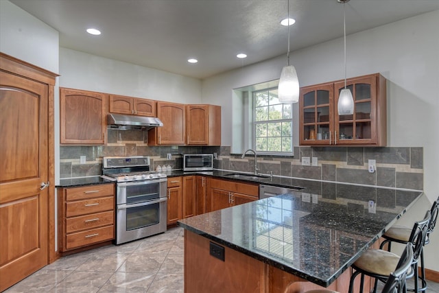 7302 N Quamish Dr, Spokane, WA 99208 - kitchen with stainless steel appliances, under cabinet range hood, glass insert cabinets, a breakfast bar area, and brown cabinetry
