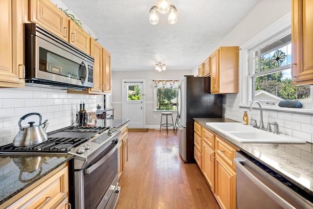 617 E 34th Ave, Spokane, WA 99203 - kitchen featuring appliances with stainless steel finishes, a textured ceiling, tasteful backsplash, light wood-style flooring, and healthy amount of natural light