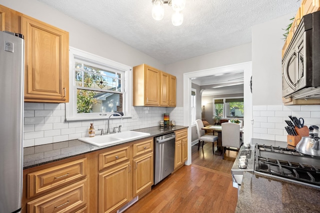 617 E 34th Ave, Spokane, WA 99203 - kitchen featuring stainless steel appliances, light wood finished floors, decorative backsplash, and a textured ceiling