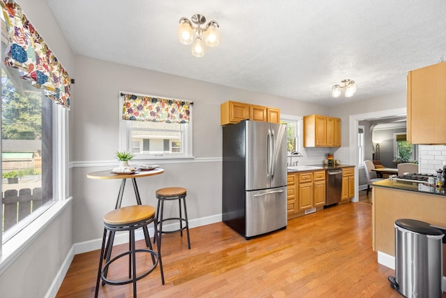 617 E 34th Ave, Spokane, WA 99203 - kitchen featuring appliances with stainless steel finishes, a chandelier, backsplash, light wood-style floors, and a textured ceiling