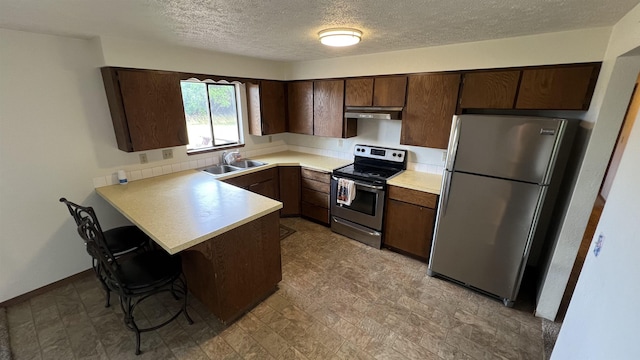 3520 N Arden Rd, Otis Orchards, WA 99027 - kitchen featuring appliances with stainless steel finishes, under cabinet range hood, a peninsula, a textured ceiling, and dark brown cabinetry