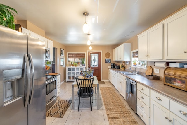 814 E Montgomery Ave, Spokane, WA 99207 - kitchen with appliances with stainless steel finishes, white cabinetry, light tile patterned flooring, and pendant lighting
