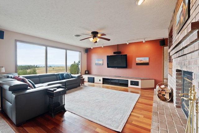 3314 W Eagles Nest Ln, Spokane, WA 99208 - living area featuring rail lighting, a brick fireplace, ceiling fan, wood finished floors, and a textured ceiling