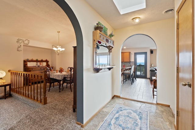 3314 W Eagles Nest Ln, Spokane, WA 99208 - corridor with arched walkways, light stone finish flooring, a chandelier, and a textured ceiling