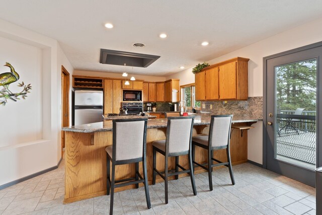 3314 W Eagles Nest Ln, Spokane, WA 99208 - kitchen featuring black appliances, tasteful backsplash, a peninsula, recessed lighting, and stone countertops