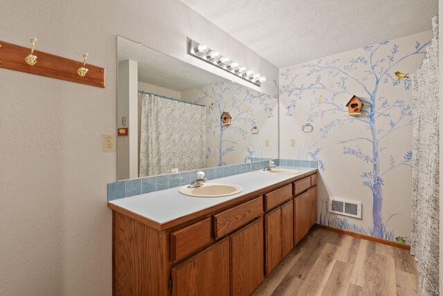 3314 W Eagles Nest Ln, Spokane, WA 99208 - bathroom featuring wood finished floors, double vanity, a textured ceiling, and wallpapered walls