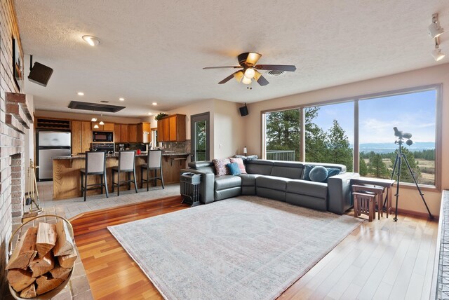 3314 W Eagles Nest Ln, Spokane, WA 99208 - living room with light wood-style flooring, a ceiling fan, a textured ceiling, and recessed lighting