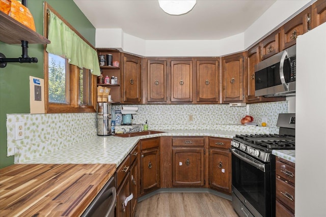 7616 E Baldwin Ave, Spokane, WA 99212 - kitchen with appliances with stainless steel finishes, light countertops, open shelves, light wood-style flooring, and tasteful backsplash