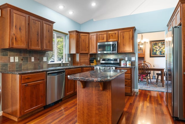 9617 N Northview Ln, Spokane, WA 99208 - kitchen with stainless steel appliances, dark wood-style floors, brown cabinetry, decorative backsplash, and a center island