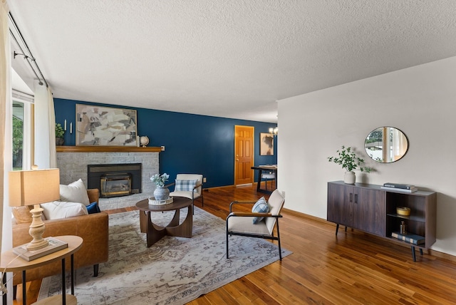 201 W Barnes Rd, Spokane, WA 99218 - living area featuring wood finished floors, a textured ceiling, and a brick fireplace
