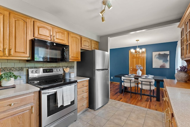 201 W Barnes Rd, Spokane, WA 99218 - kitchen featuring stainless steel appliances, light tile patterned flooring, light countertops, backsplash, and a chandelier