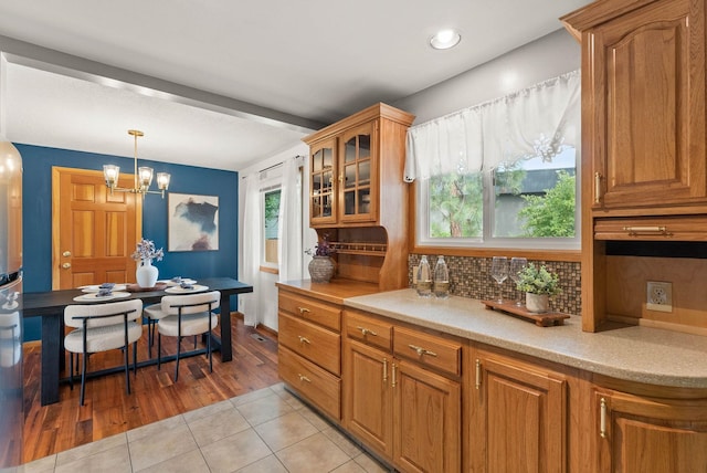 201 W Barnes Rd, Spokane, WA 99218 - kitchen featuring light tile patterned flooring, tasteful backsplash, glass insert cabinets, brown cabinetry, and a chandelier