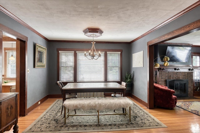 927 W 19th Ave, Spokane, WA 99203 - dining room featuring light wood finished floors, a chandelier, a fireplace, and ornamental molding