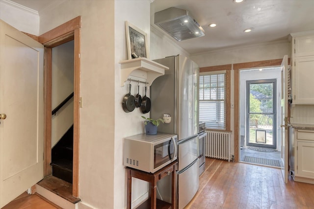 927 W 19th Ave, Spokane, WA 99203 - kitchen with radiator heating unit, ornamental molding, light wood finished floors, white cabinets, and recessed lighting