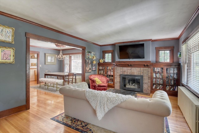 927 W 19th Ave, Spokane, WA 99203 - living area featuring radiator heating unit, a chandelier, light wood-style floors, a brick fireplace, and crown molding