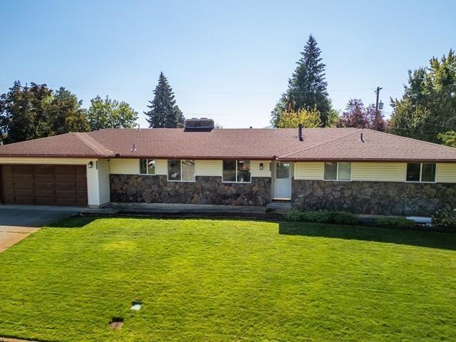 10108 E 19th Ave, Spokane Valley, WA 99206 - ranch-style house featuring stone siding, a garage, concrete driveway, and a front yard