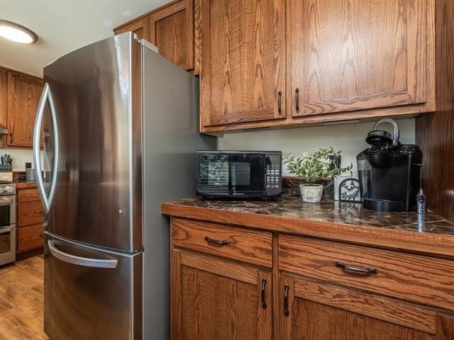10108 E 19th Ave, Spokane Valley, WA 99206 - kitchen featuring stainless steel appliances, brown cabinets, dark countertops, and light wood-type flooring