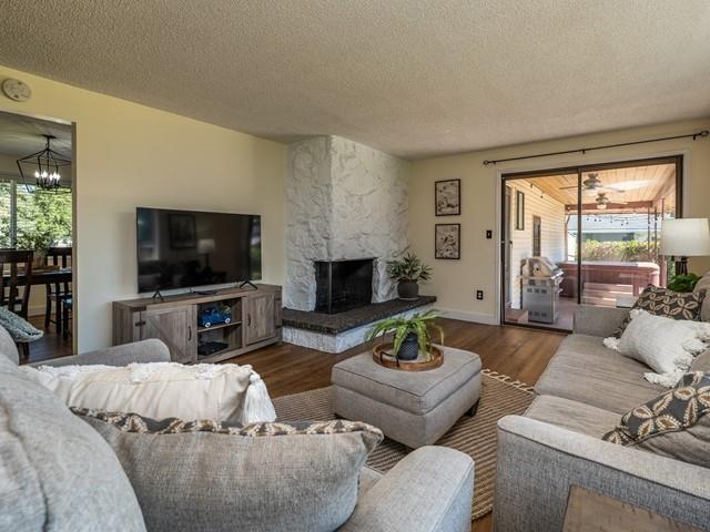 10108 E 19th Ave, Spokane Valley, WA 99206 - living area with a chandelier, wood finished floors, a textured ceiling, and a large fireplace