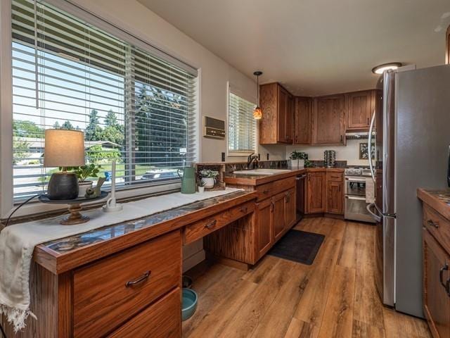 10108 E 19th Ave, Spokane Valley, WA 99206 - kitchen featuring stainless steel appliances, brown cabinetry, light wood-style floors, and plenty of natural light