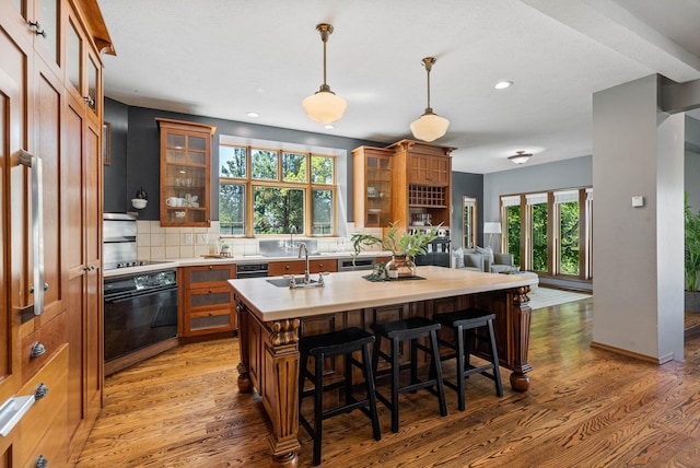 6204 E Custer Ln, Spokane, WA 99223 - kitchen with brown cabinetry, light countertops, wood finished floors, decorative backsplash, and stove
