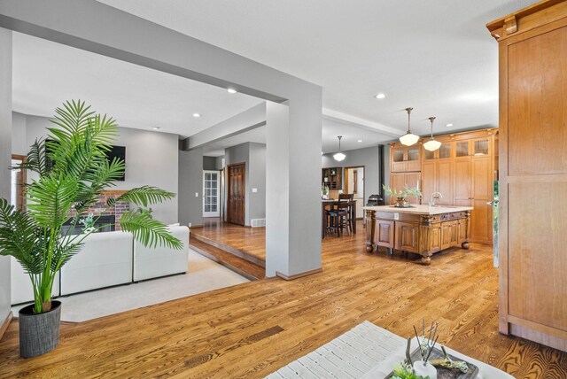 6204 E Custer Ln, Spokane, WA 99223 - kitchen featuring light wood finished floors, a center island with sink, recessed lighting, glass insert cabinets, and light countertops