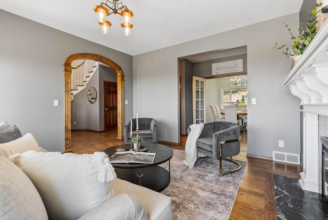 6204 E Custer Ln, Spokane, WA 99223 - living room with a chandelier, arched walkways, wood finished floors, a high end fireplace, and stairway