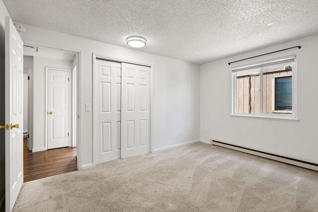 6125 N Addison St, Spokane, WA 99208 - unfurnished bedroom with carpet flooring, a baseboard heating unit, a textured ceiling, and a closet
