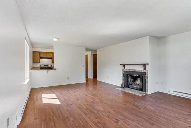 6125 N Addison St, Spokane, WA 99208 - unfurnished living room with baseboard heating, a baseboard radiator, wood finished floors, a tile fireplace, and a textured ceiling