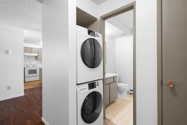 6125 N Addison St, Spokane, WA 99208 - washroom featuring stacked washing machine and dryer, light wood-type flooring, a textured ceiling, and a baseboard heating unit