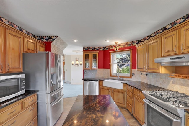 8722 E Boardwalk Ln, Spokane, WA 99212 - kitchen featuring stainless steel appliances, under cabinet range hood, a chandelier, tasteful backsplash, and brown cabinetry