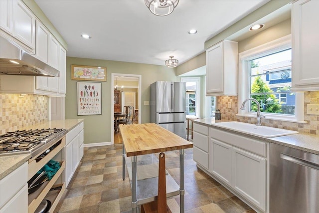 2718 S Hatch St, Spokane, WA 99203 - kitchen featuring appliances with stainless steel finishes, white cabinets, backsplash, recessed lighting, and range hood
