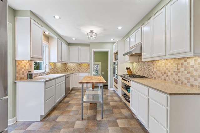 2718 S Hatch St, Spokane, WA 99203 - kitchen with under cabinet range hood, recessed lighting, stone finish floors, white cabinets, and appliances with stainless steel finishes