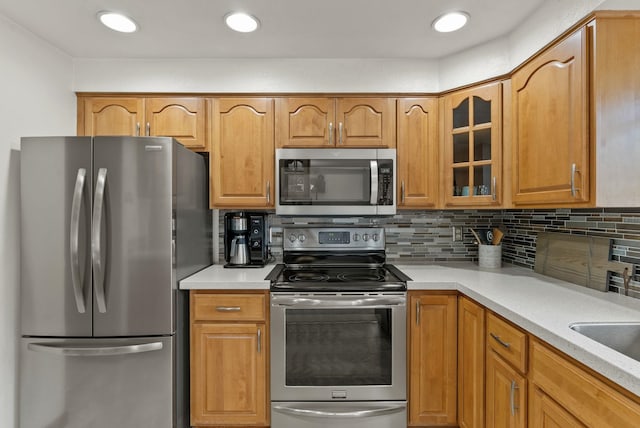 11919 S Player Dr, Spokane, WA 99223 - kitchen featuring stainless steel appliances, glass insert cabinets, light countertops, and decorative backsplash