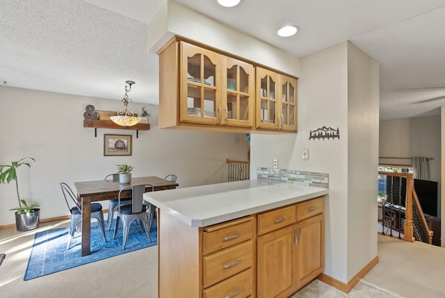 11919 S Player Dr, Spokane, WA 99223 - kitchen with light carpet, glass insert cabinets, light countertops, a textured ceiling, and decorative light fixtures