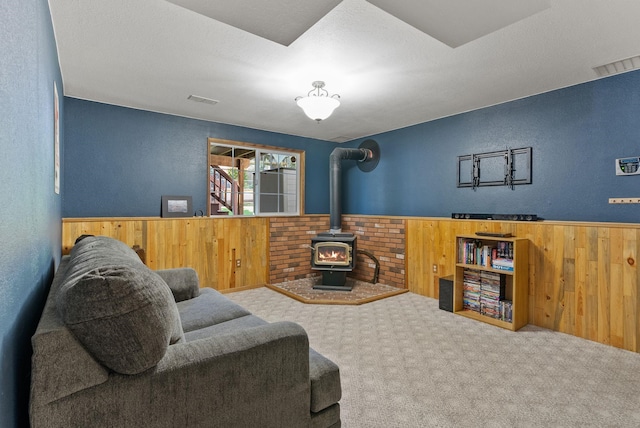 11919 S Player Dr, Spokane, WA 99223 - living area with a wood stove, wood walls, carpet flooring, a textured wall, and a wainscoted wall