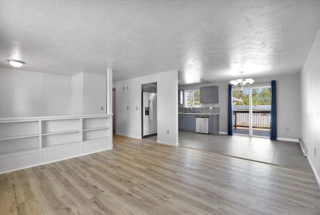 10109 E 9th Ave, Spokane Valley, WA 99206 - unfurnished living room with a chandelier, light wood finished floors, a baseboard radiator, and a textured ceiling