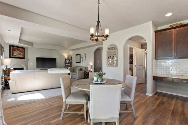 1115 S Mcmillan Rd, Spokane Valley, WA 99016 - dining room with arched walkways, dark wood-style floors, a chandelier, and a raised ceiling