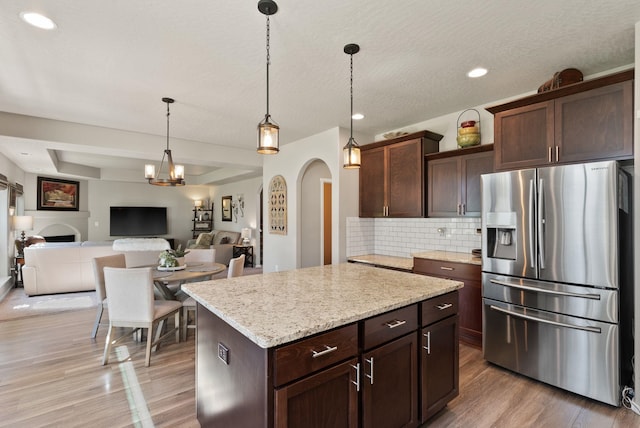 1115 S Mcmillan Rd, Spokane Valley, WA 99016 - kitchen featuring stainless steel fridge, light wood-style floors, tasteful backsplash, arched walkways, and dark brown cabinetry