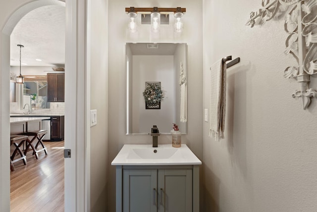 1115 S Mcmillan Rd, Spokane Valley, WA 99016 - bathroom featuring wood finished floors, vanity, backsplash, and a textured ceiling