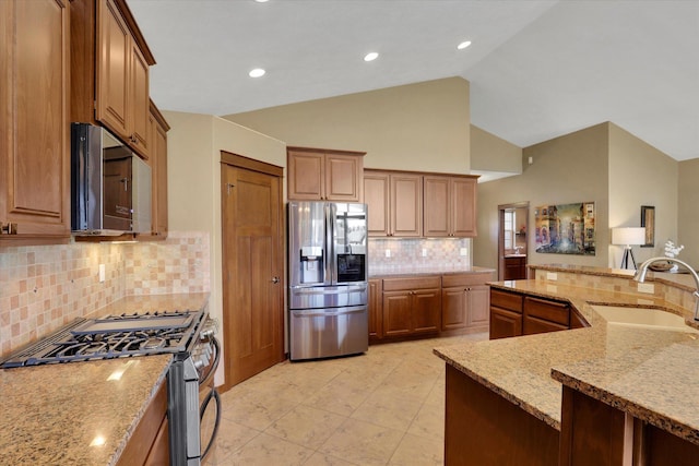 202 E Alexa Ct, Spokane, WA 99208 - kitchen with stainless steel appliances, light stone counters, backsplash, brown cabinets, and high vaulted ceiling