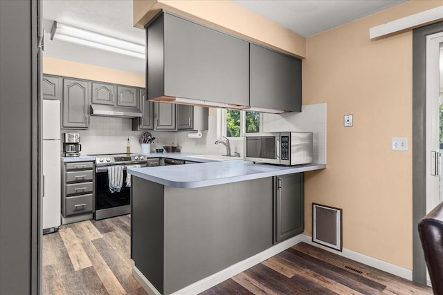 14020 S Sharp Ave, Spokane Valley, WA 99216 - kitchen with appliances with stainless steel finishes, gray cabinets, a peninsula, under cabinet range hood, and dark wood finished floors