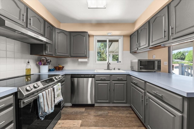 14020 S Sharp Ave, Spokane Valley, WA 99216 - kitchen featuring appliances with stainless steel finishes, gray cabinets, a peninsula, extractor fan, and dark wood-type flooring