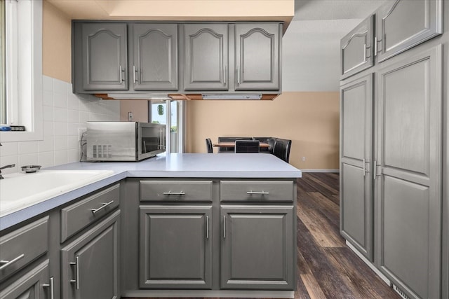 14020 S Sharp Ave, Spokane Valley, WA 99216 - kitchen with gray cabinets, stainless steel microwave, a peninsula, dark wood-type flooring, and light countertops