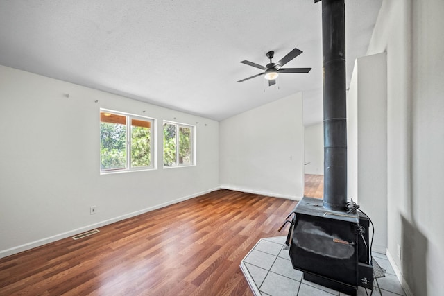 9801 Lakeshore Dr, Sagle, ID 83860 - unfurnished living room with a wood stove, vaulted ceiling, a ceiling fan, and wood finished floors
