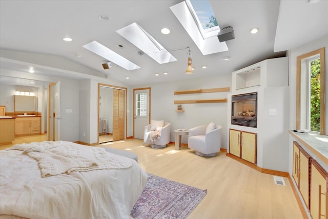 2714 E 11th Ave, Spokane, WA 99202 - bedroom with vaulted ceiling, a skylight, light wood-style flooring, recessed lighting, and a glass covered fireplace