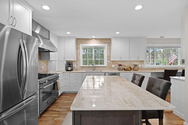 3929 S Best Ct, Veradale, WA 99037 - kitchen with appliances with stainless steel finishes, wall chimney exhaust hood, light wood finished floors, tasteful backsplash, and recessed lighting