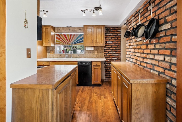 5003 N Normandie St, Spokane, WA 99205 - kitchen with dishwasher, hardwood / wood-style flooring, tasteful backsplash, brown cabinets, and brick wall